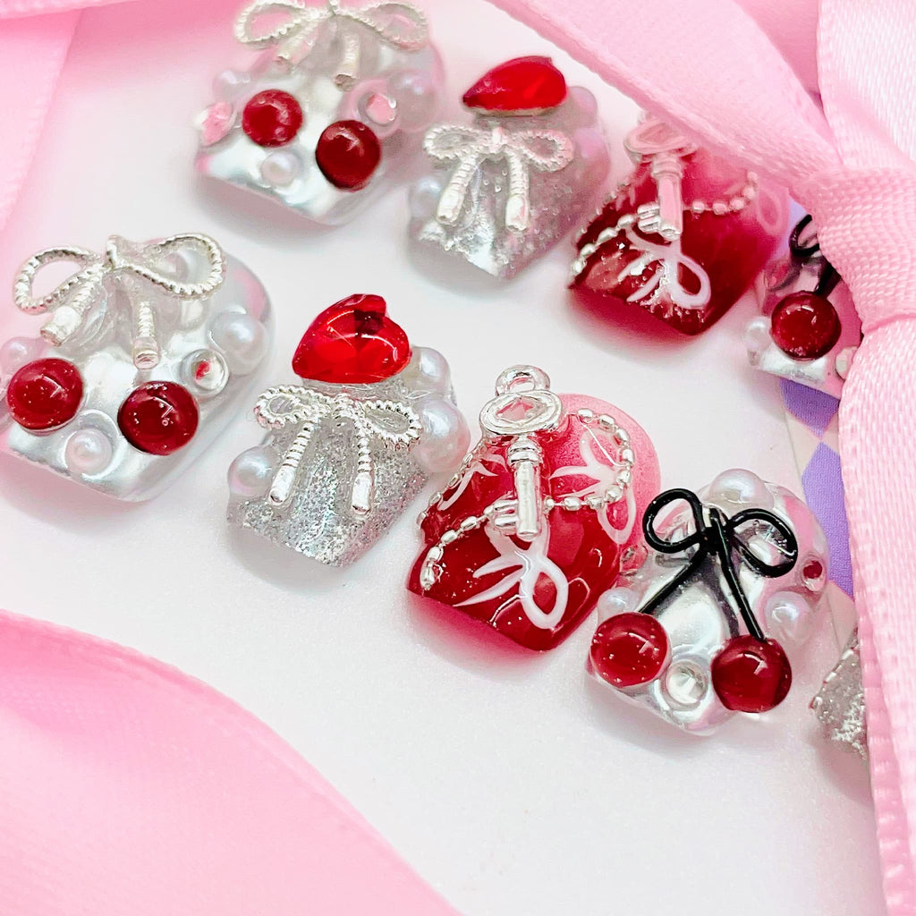 Decorative heart-shaped ornaments with red cherries, silver bows, and keys 