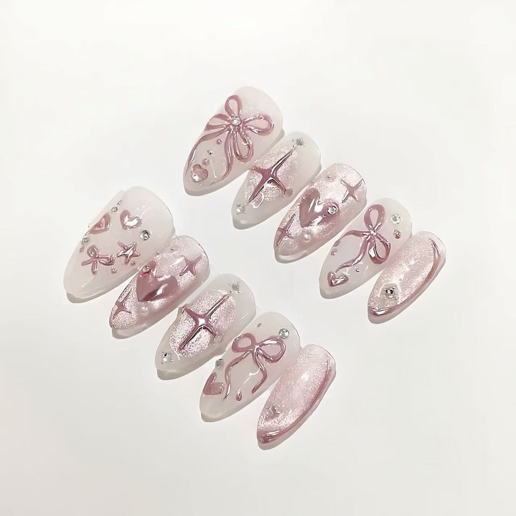 Set of decorative false nails with pink bows and rhinestones on a light background
