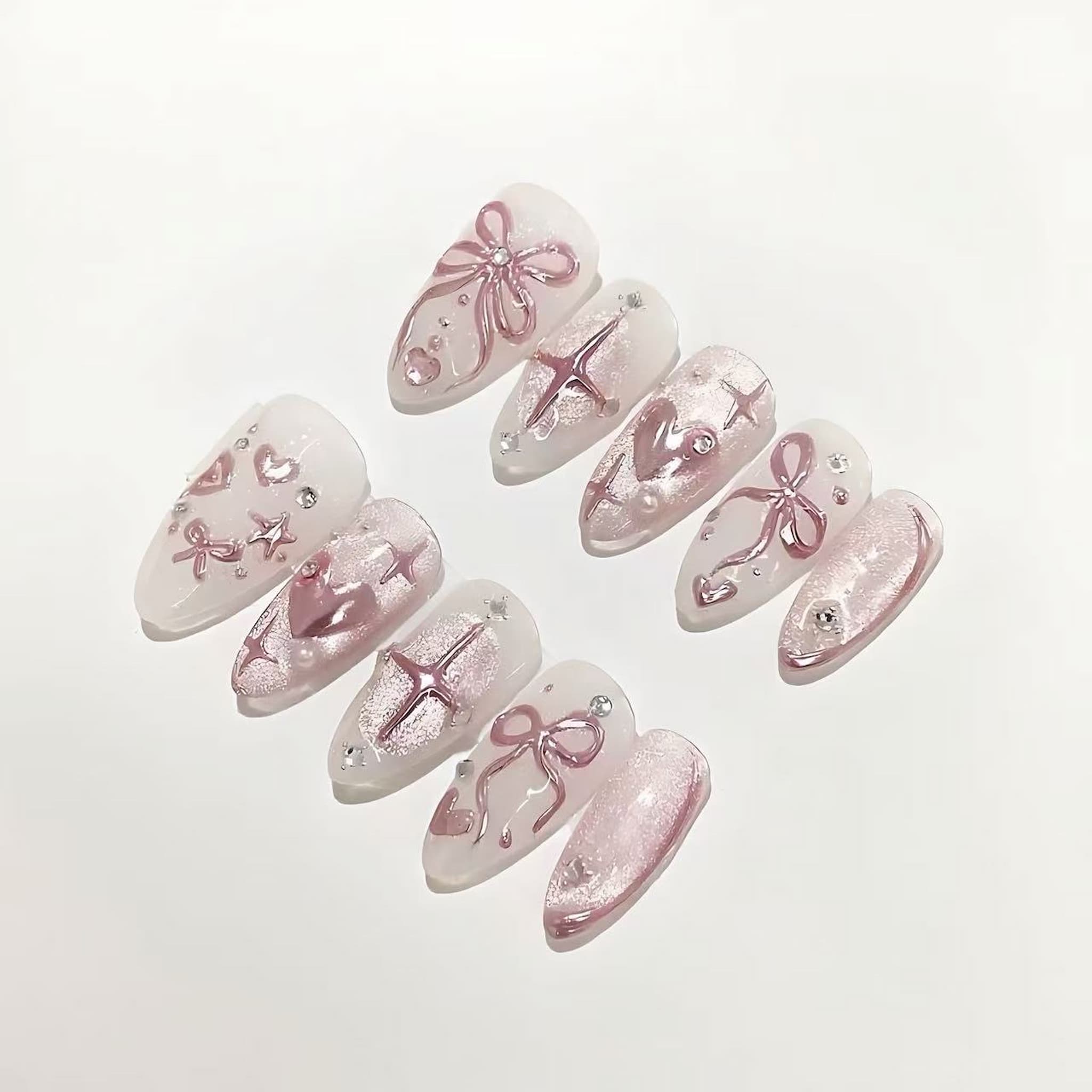 Set of decorative false nails with pink bows and rhinestones on a light background