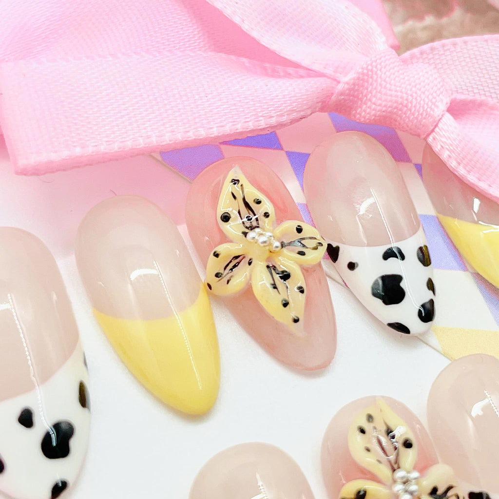 medium length nude almond press on nails with cow animal print design and daisy