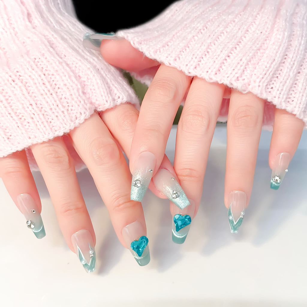 A set of false nails showcasing a mermaid-inspired design with teal colors and glossy finish
