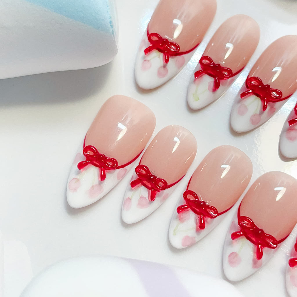 medium length white almond press on nails with cherries and bow design