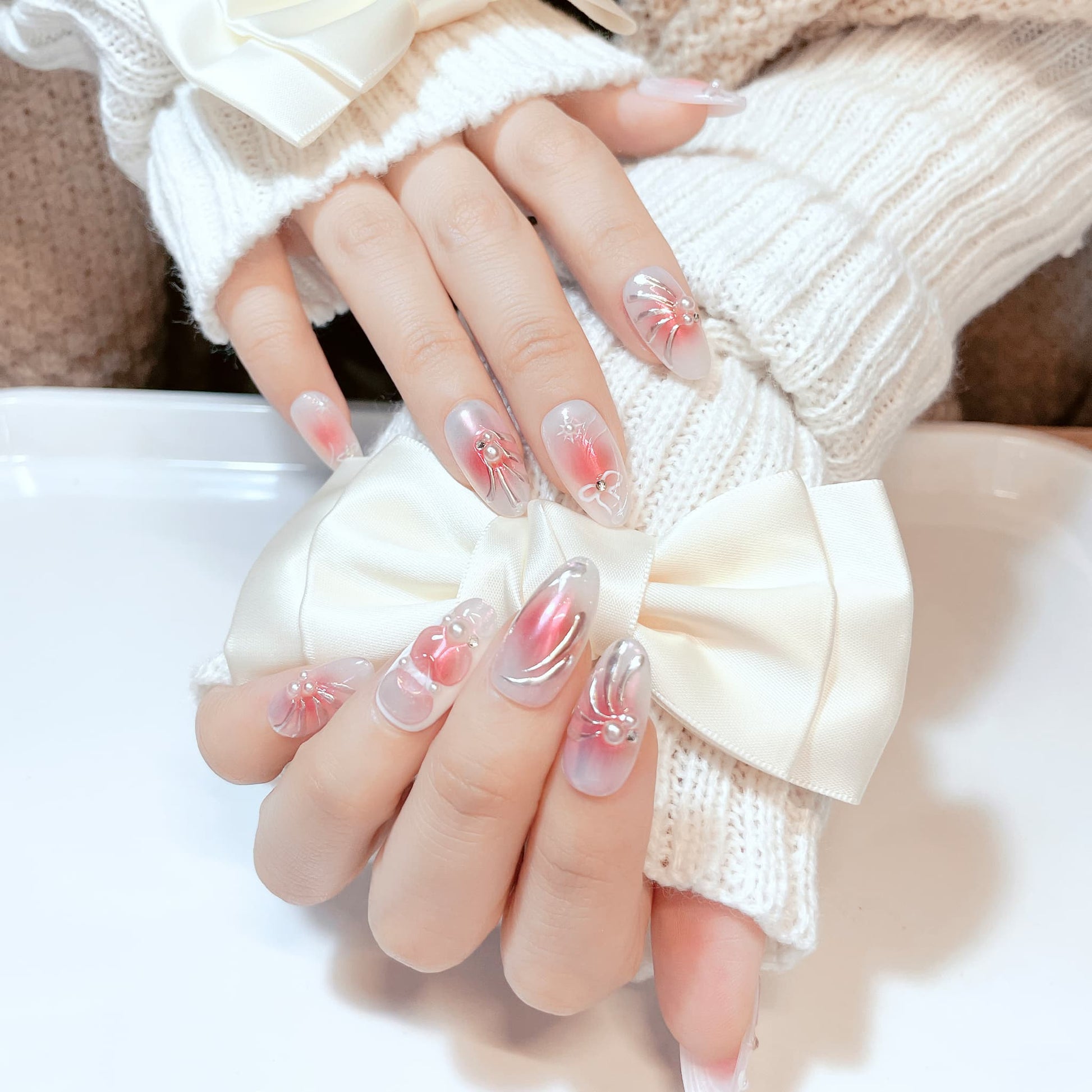 medium length pink almond press on nails with bow and pearl design