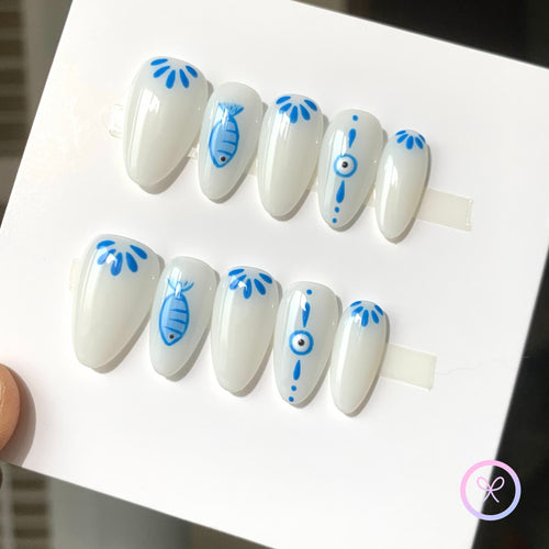 oceanic white glossy almond press on nails with fish and eye motifs