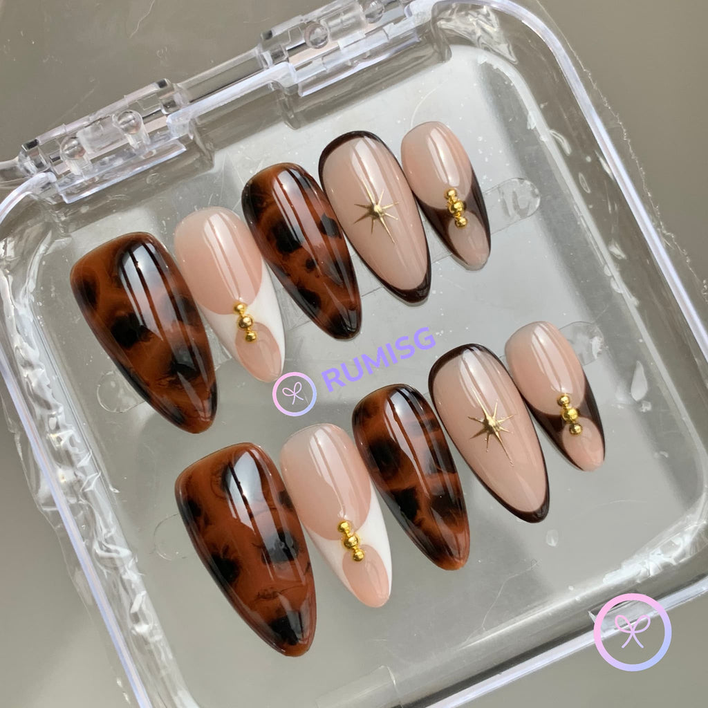 animal print nude glossy medium almond press on nails with gold beads and tortoiseshell