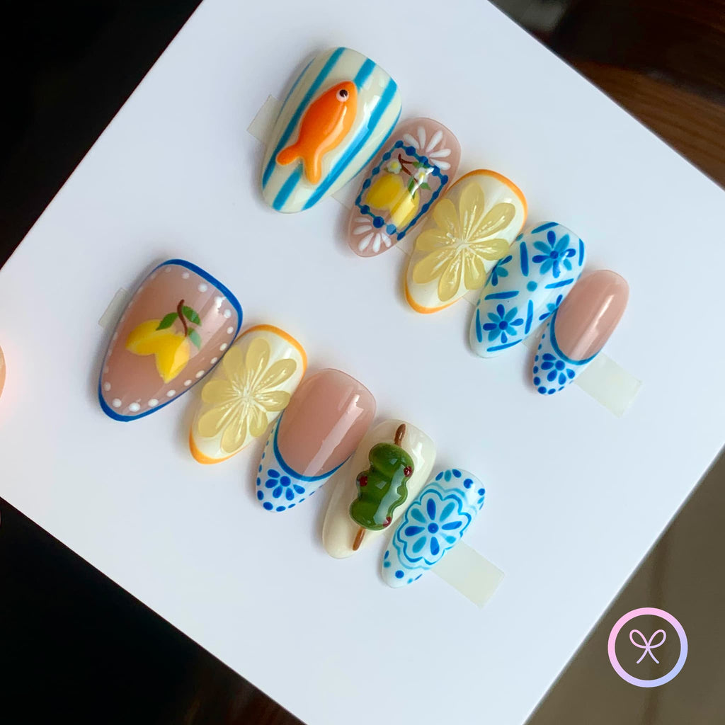amalfi coast yellow glossy short almond press on nails with tuna and lemon motifs along side tiles and porcelain