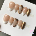 elegant nude chrome short almond press on nails with swirls and pearl motif. french tips and golden chrome