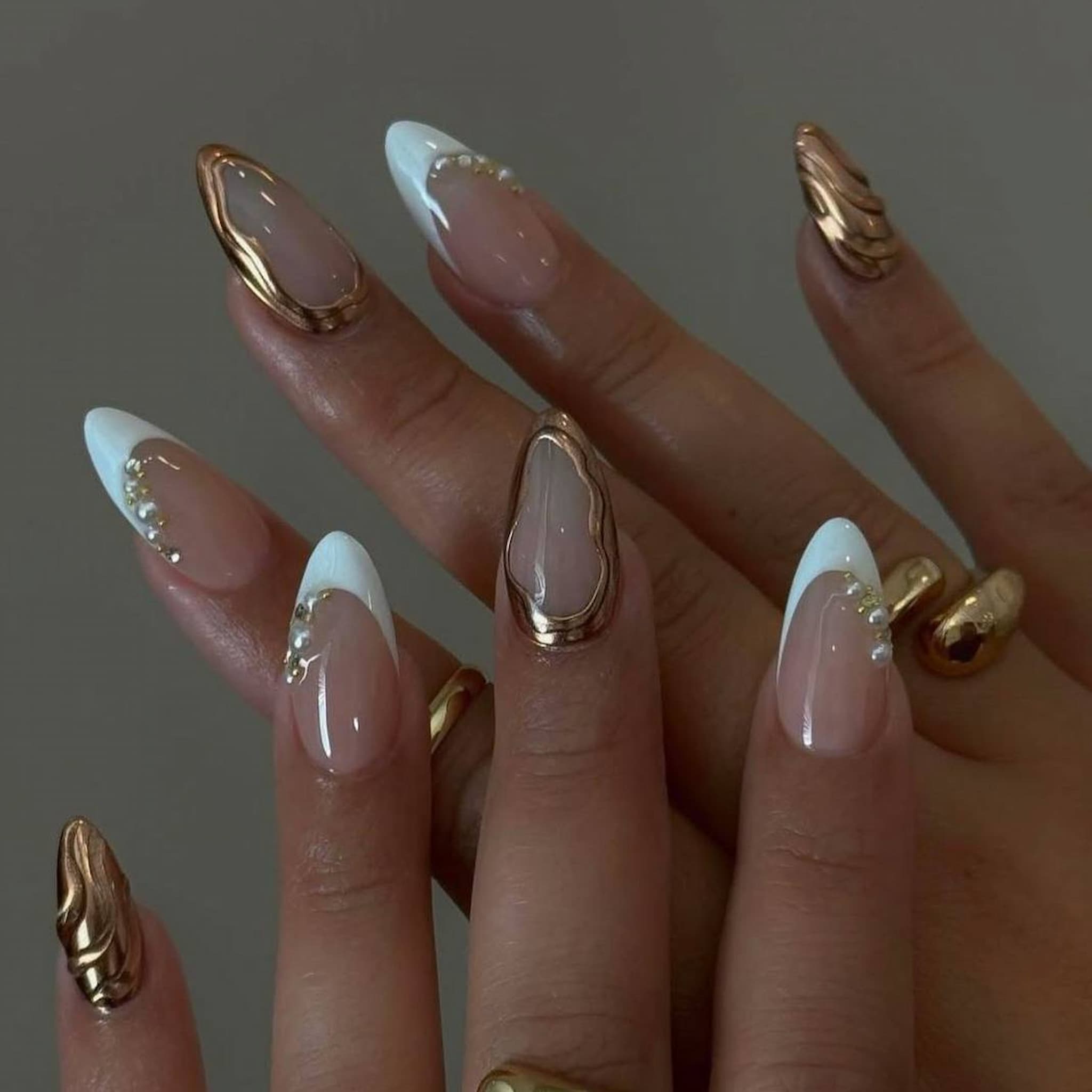 elegant nude chrome short almond press on nails with swirls and pearl motif. french tips and golden chrome