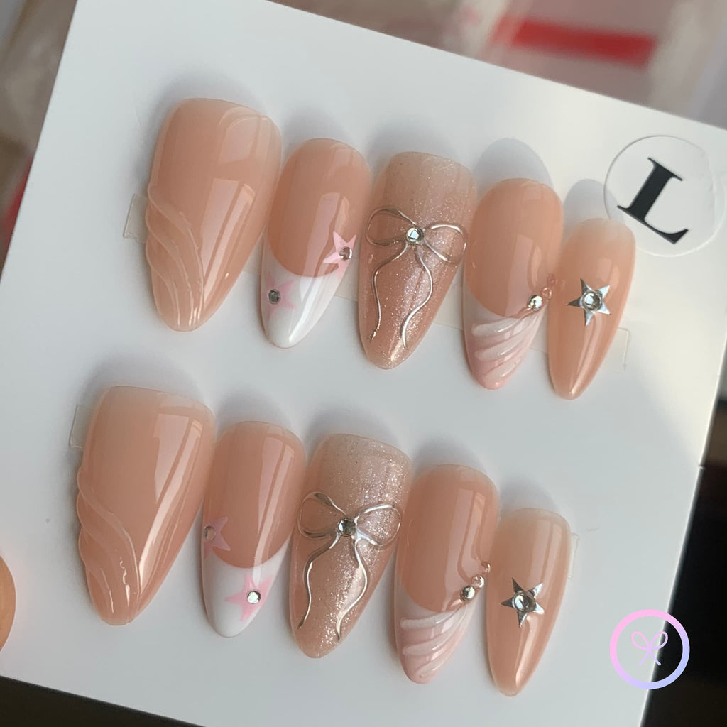 coquette nude glossy medium almond press on nails with metallic bows and stars , french tips
