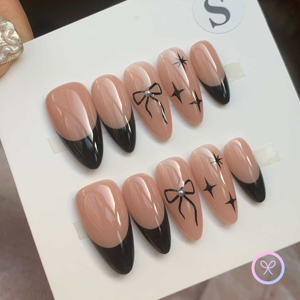 minimalist nude glossy medium almond press on nails with black bows and star motifs