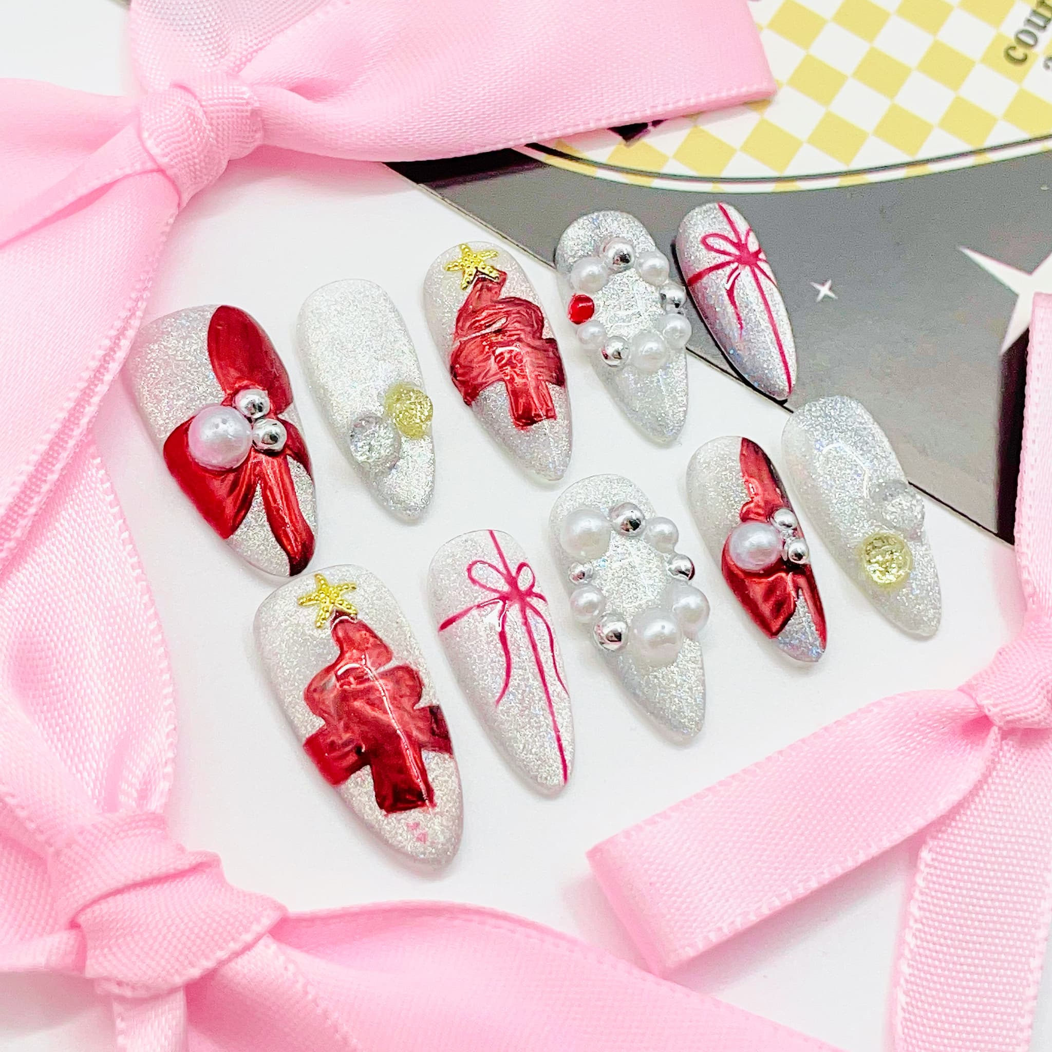 Decorative nail art with red bows and pearls