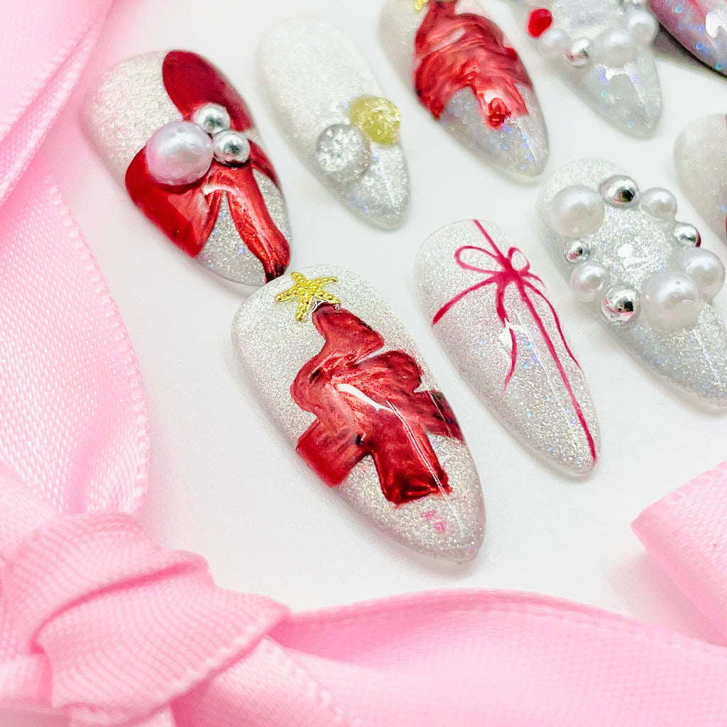 Decorative nail art with red bows and pearls