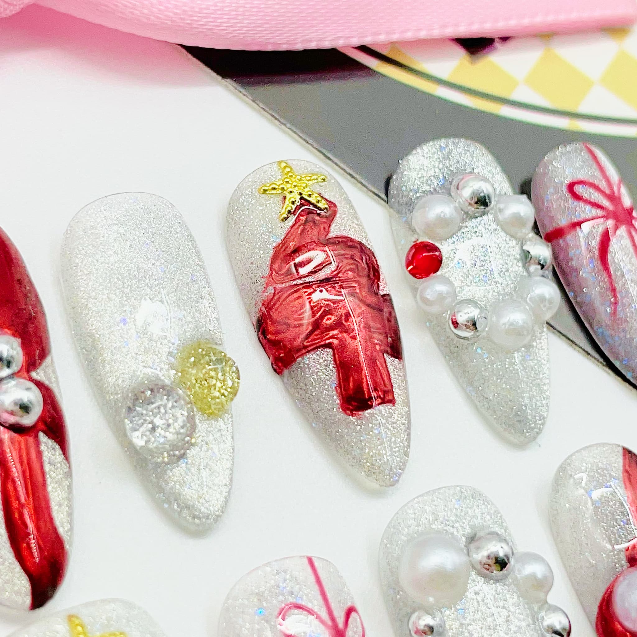 Decorative nail art with red bows and pearls