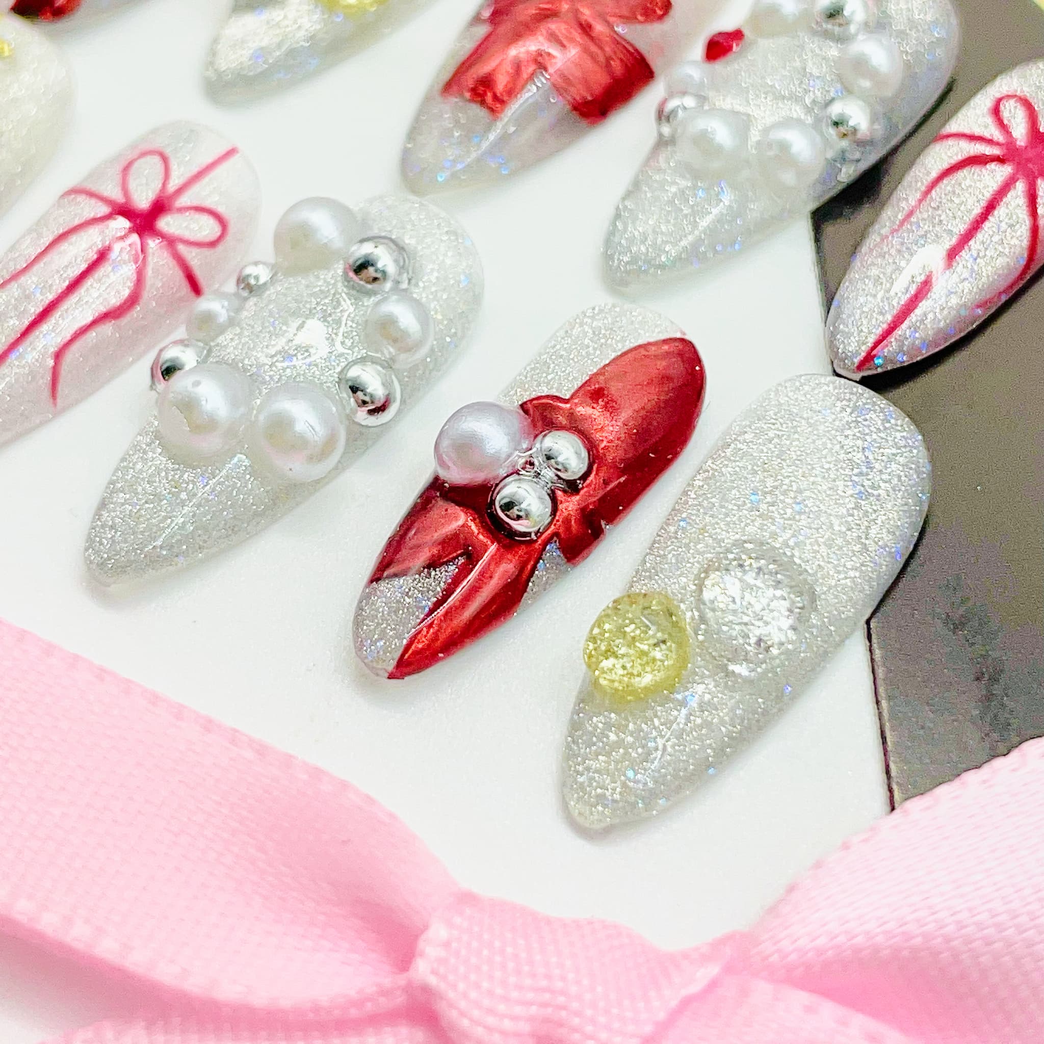 Decorative nail art with red bows and pearls