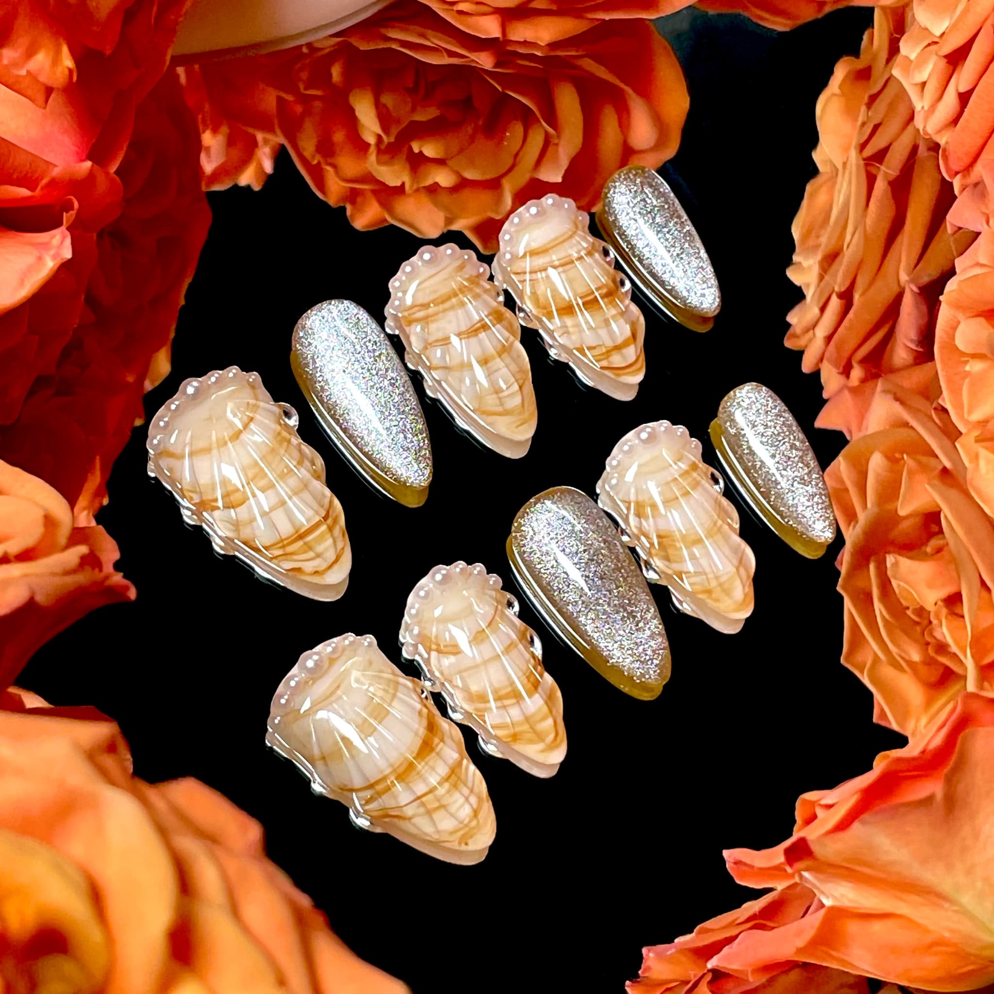medium length gold almond press on nails with seashell designs and silver glitters