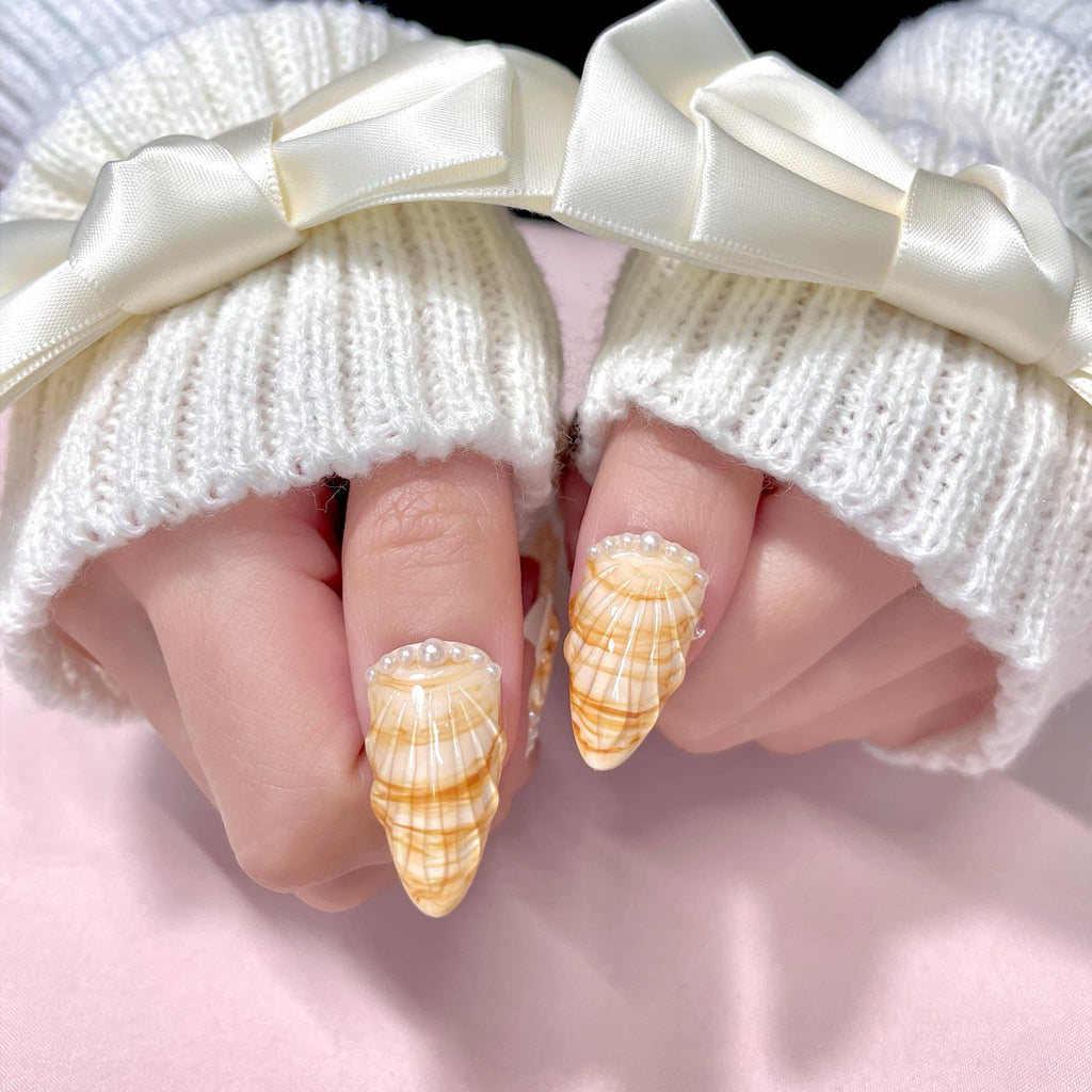 medium length gold almond press on nails with seashell designs and silver glitters