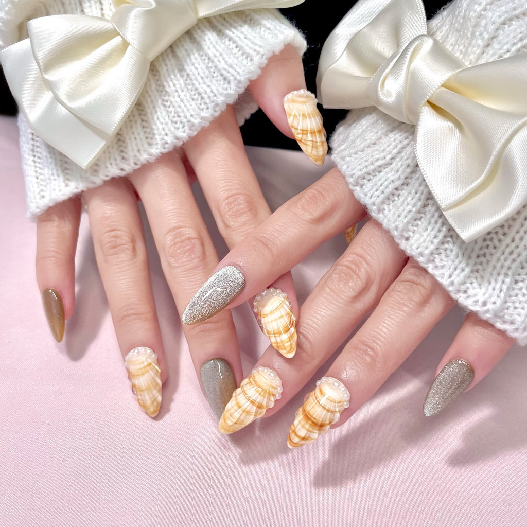 medium length gold almond press on nails with seashell designs and silver glitters