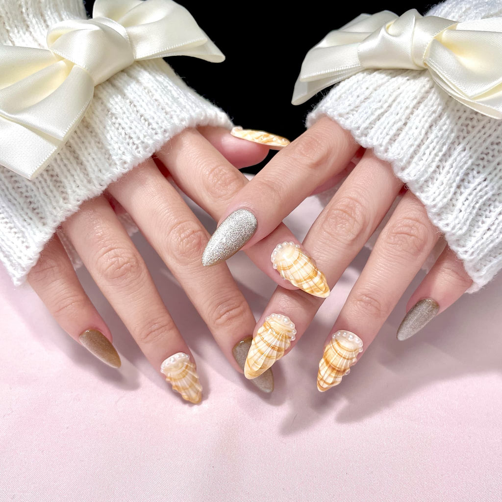 medium length gold almond press on nails with seashell designs and silver glitters