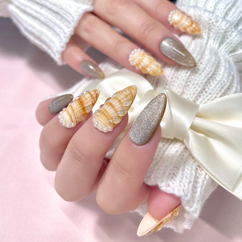 medium length gold almond press on nails with seashell designs and silver glitters