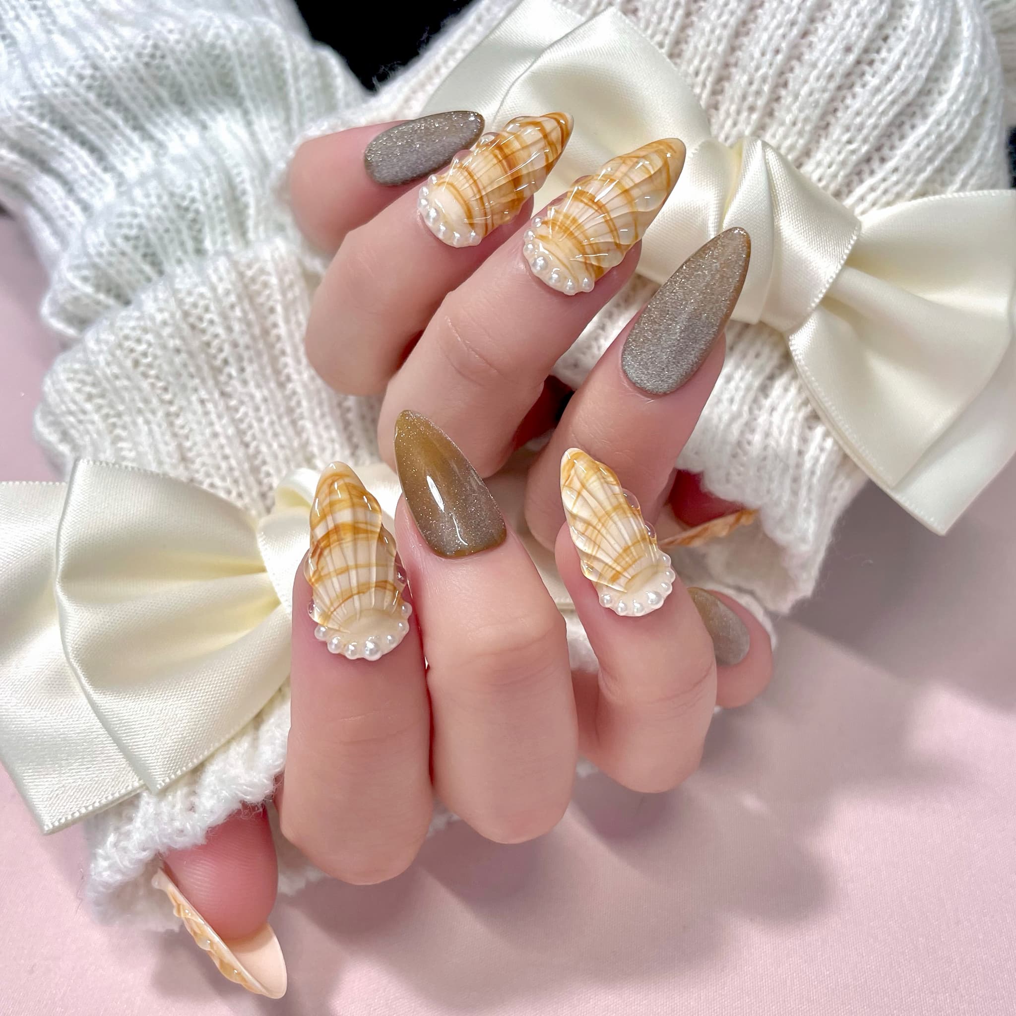 medium length gold almond press on nails with seashell designs and silver glitters