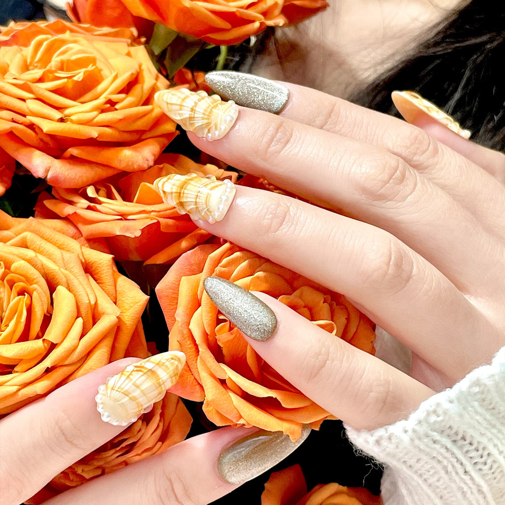 medium length gold almond press on nails with seashell designs and silver glitters